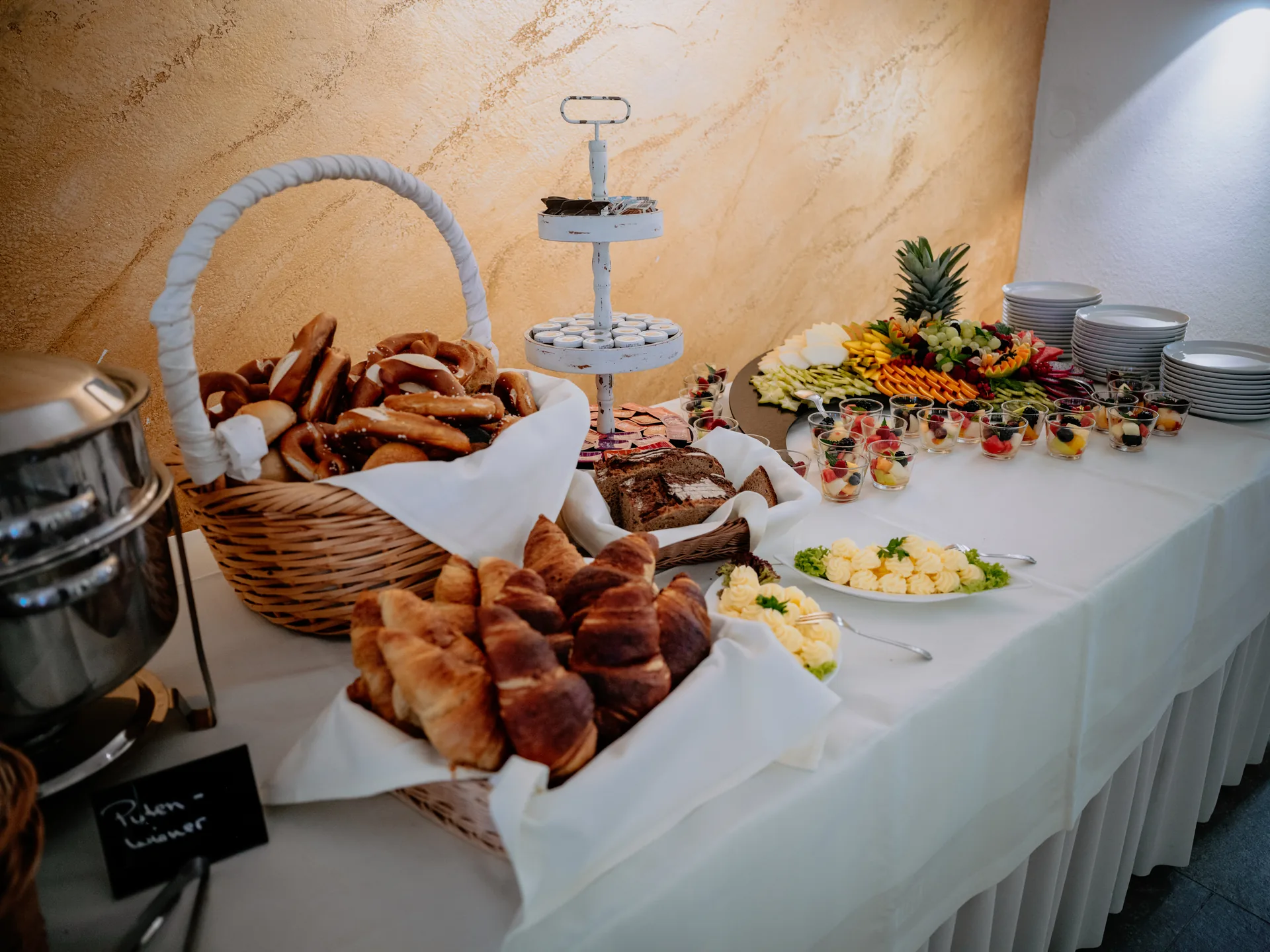 Brunchbuffet mit Croissants, Brezeln, Brot und frischen Früchten im Schloss