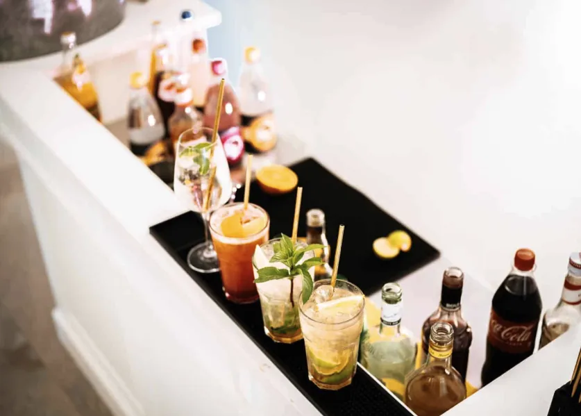 Cocktails und Flaschen auf einer weißen Bartheke