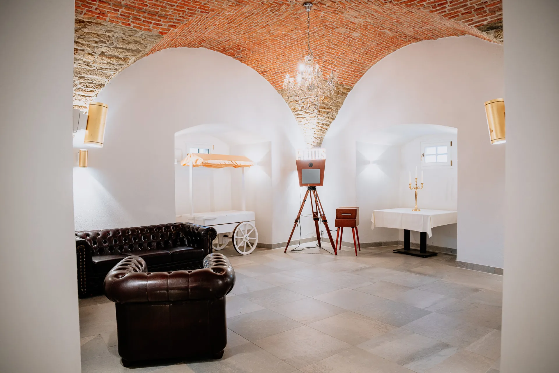 Foyer mit Ziegelgewölbe, Kristallleuchter, Chesterfield-Ledersofa, Candy-Wagen und historischer Fotobox