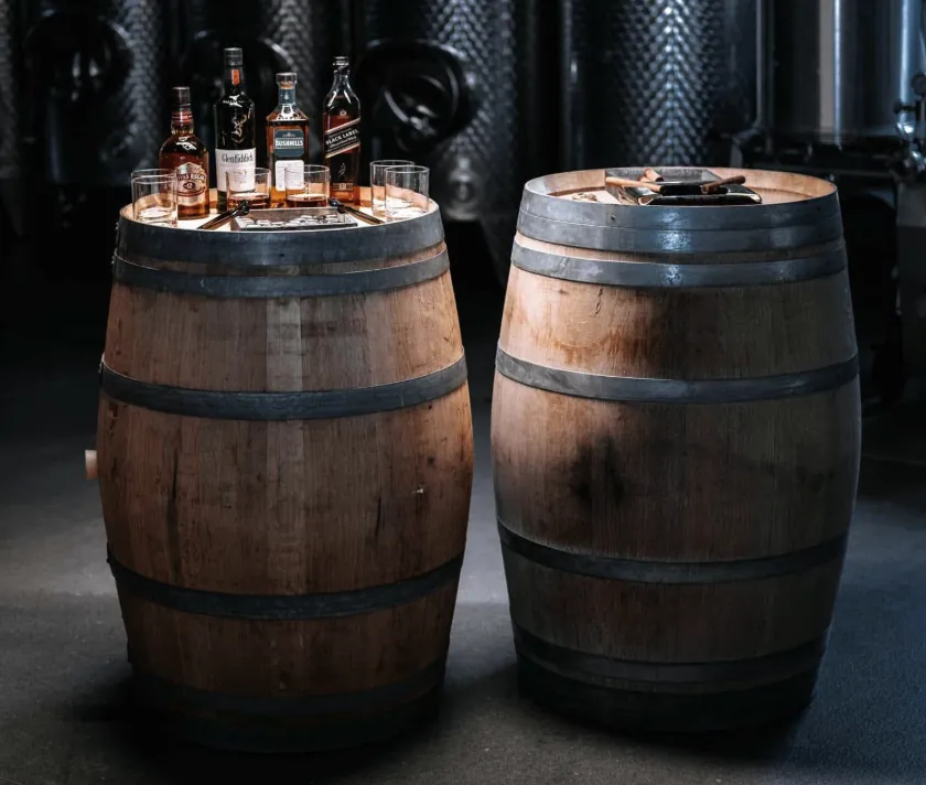 Zwei Holzfässer mit Whiskeyflaschen, Gläsern und Zigarren