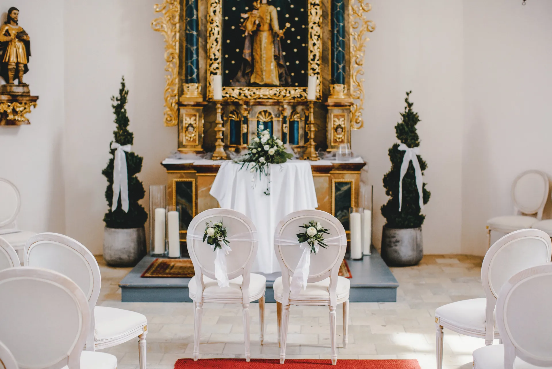Barocker Goldaltar der Schlosskapelle mit Blumenschmuck und zwei weißen Stühlen für das Brautpaar