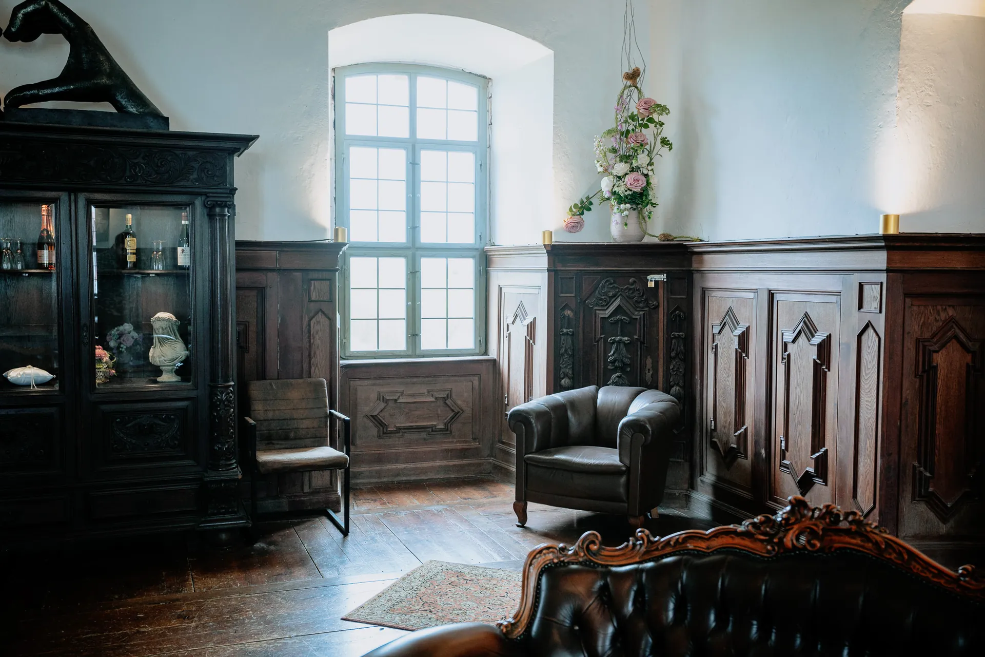 Lederne Sitzgruppe mit Blumenschmuck unter dem Kristallleuchter im Brautraum