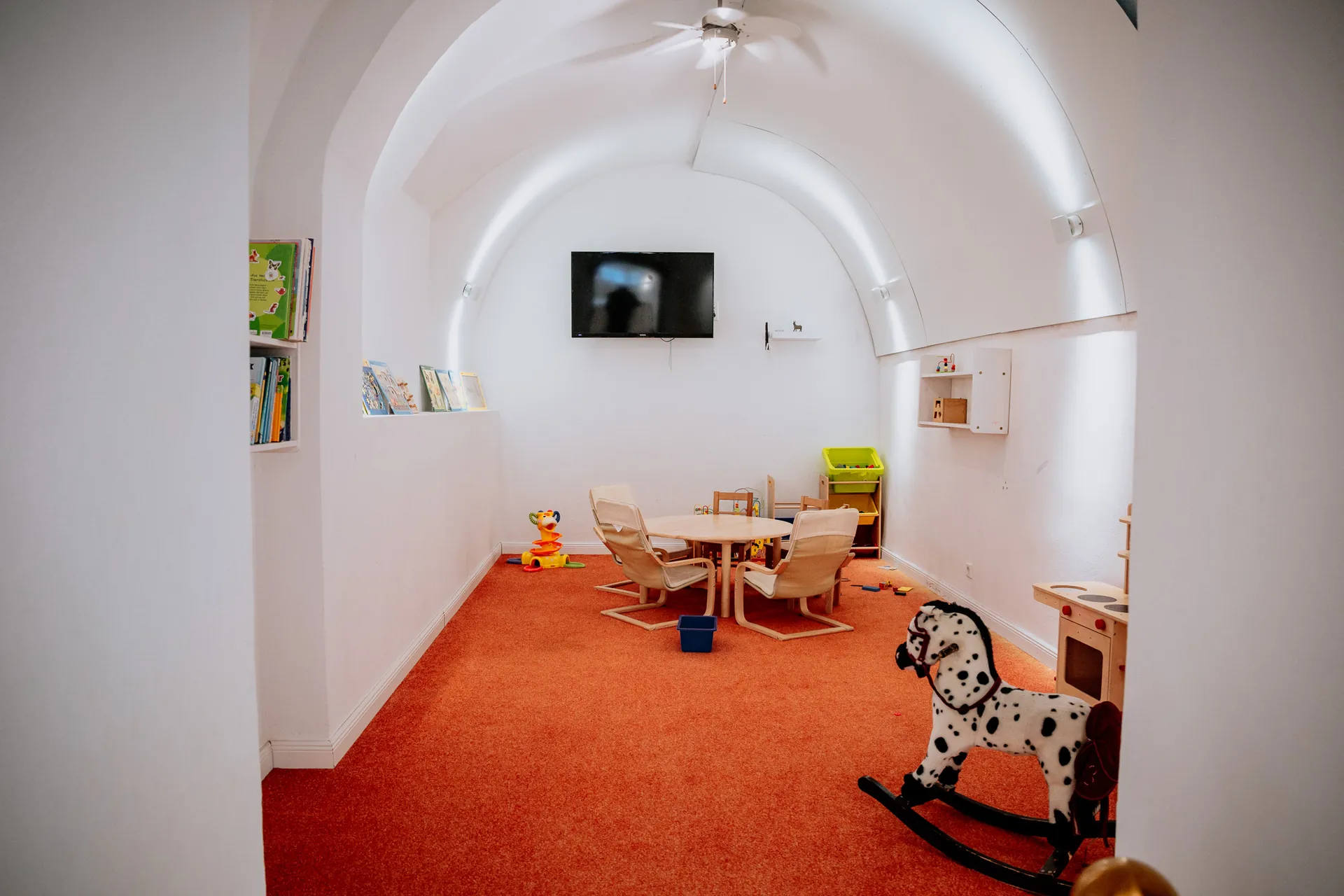 Kinderspielzimmer im Gewölbe mit Spielküche, Schaukelpferd, Kindertisch und Bilderbüchern