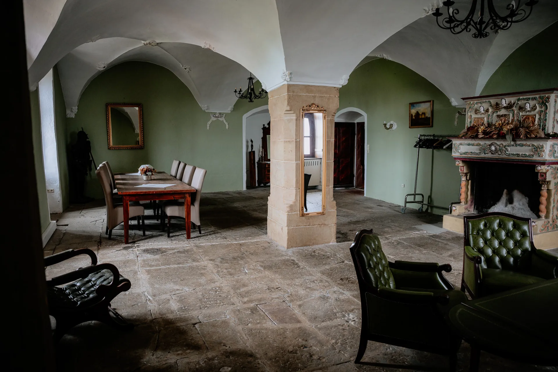 Historischer Festsaal mit grünen Wänden, Kamin und Ledersesseln